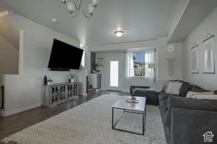 Open-concept room featuring wood-finish flooring, a multi-arm overhead chandelier, recessed ceiling lighting, and a glass-paneled exterior door