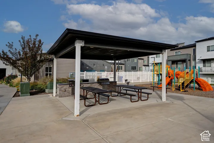 Covered outdoor pavilion featuring a stone-clad built-in grill and concrete patio space