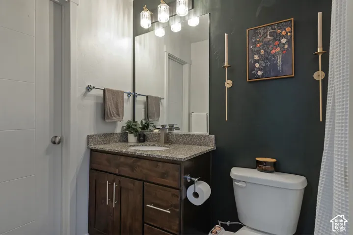 Dark-stained wood vanity featuring a stone-composite countertop, undermount sink, multi-light vanity fixture, and large rectangular mirror