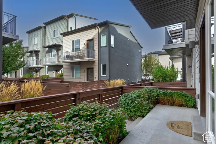Concrete patio with horizontal wood fencing, landscaped shrubbery, and multi-story exteriors featuring mixed siding and metal balcony railings