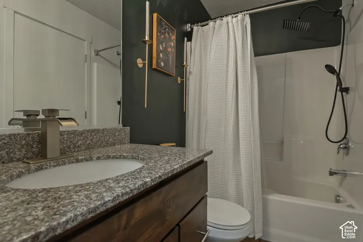 Bathroom vanity with stone-finish countertop, undermount sink, and metallic finish faucet, paired with a shower-tub combination featuring an overhead rainfall showerhead and a secondary handheld wand