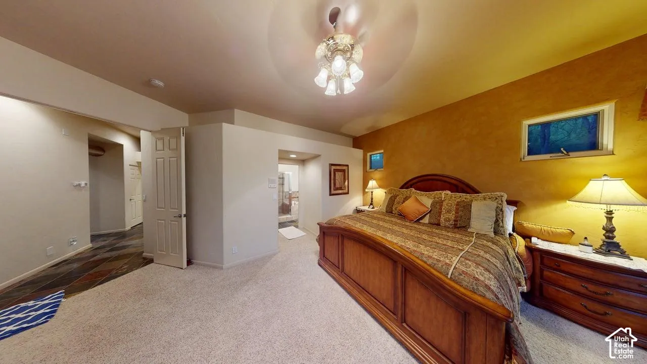Room featuring neutral wall-to-wall carpeting, textured accent wall, multi-bulb ceiling fixture, and horizontal transom windows