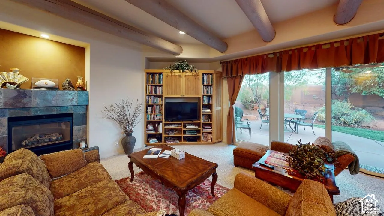 Exposed log ceiling beams, floor-to-ceiling stone-tiled fireplace, custom built-in wood cabinetry, and sliding glass doors with direct exterior access