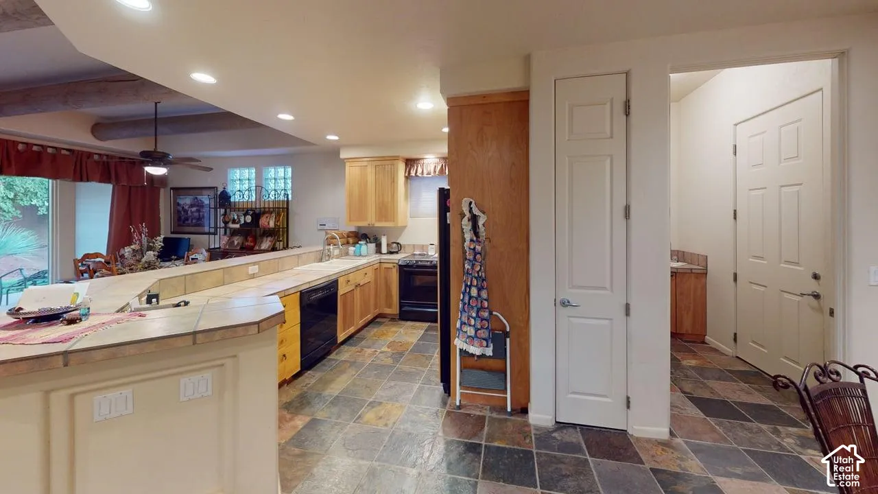 Kitchen featuring slate tile flooring, natural wood cabinetry, tile-surround breakfast bar, recessed lighting, and built-in appliances