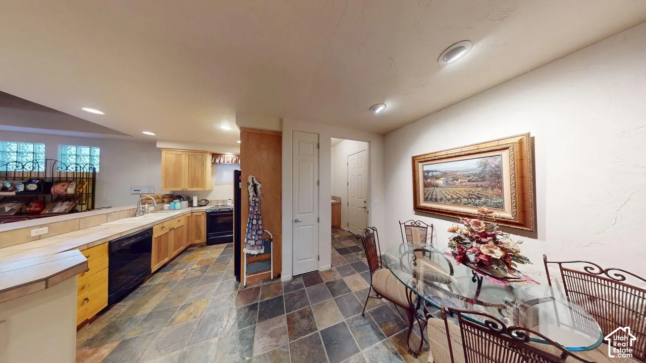 Kitchen featuring natural wood cabinetry, tile flooring, and integrated black appliances