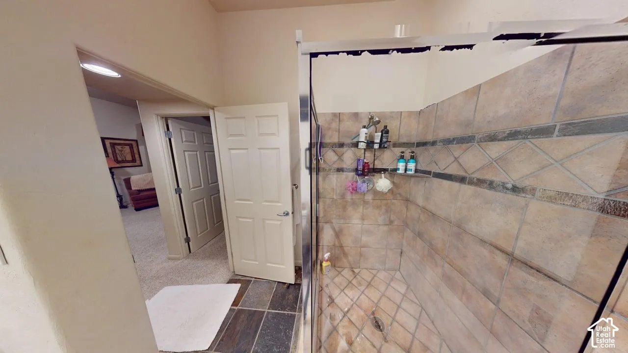 Walk-in shower featuring glass paneling, multi-tone ceramic wall tiles, decorative accent tile inlay, and large-format floor tiles