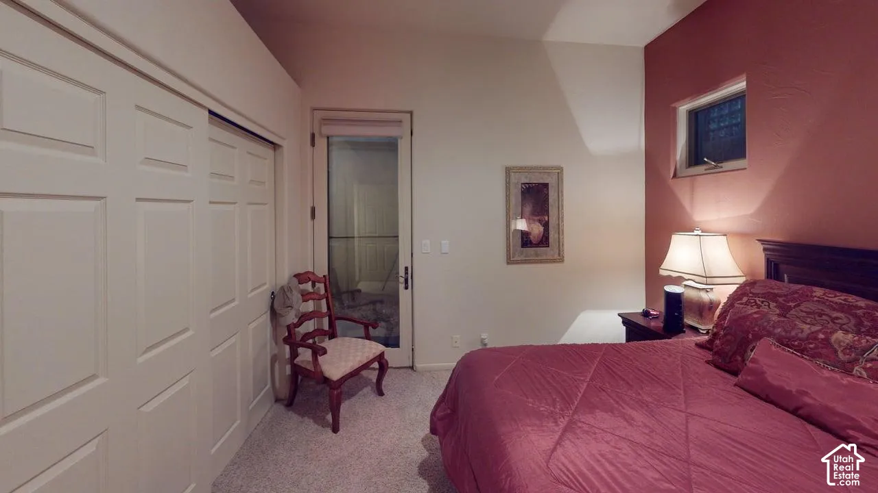 Room featuring vaulted ceilings, carpeted flooring, sliding closet doors, and a glass-paneled exterior door