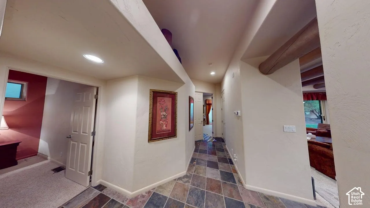 Hallway featuring multi-tone slate flooring, recessed lighting, and decorative wood beam ceiling accents