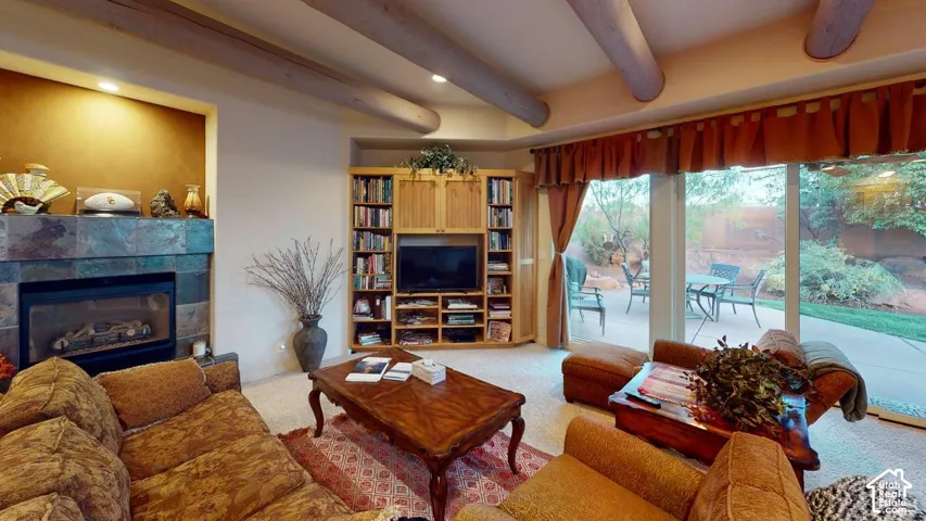 Exposed log ceiling beams, floor-to-ceiling stone-tiled fireplace, custom built-in wood cabinetry, and sliding glass doors with direct exterior access