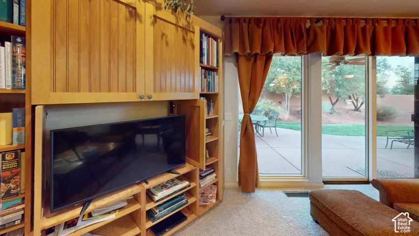 Built-in floor-to-ceiling light wood cabinetry with open shelving and sliding door panels, expansive glass sliding doors, and concrete patio