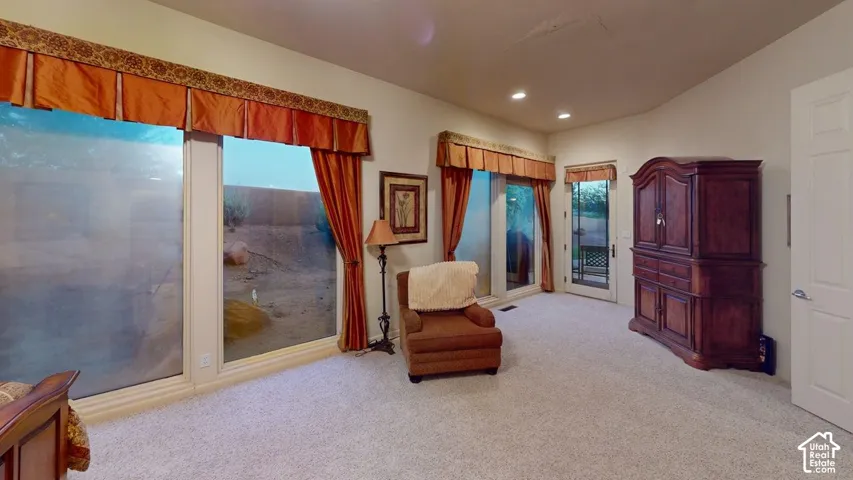 Vaulted ceilings, large windows with full-length glass panes, recessed lighting, and a glass-paneled exterior door