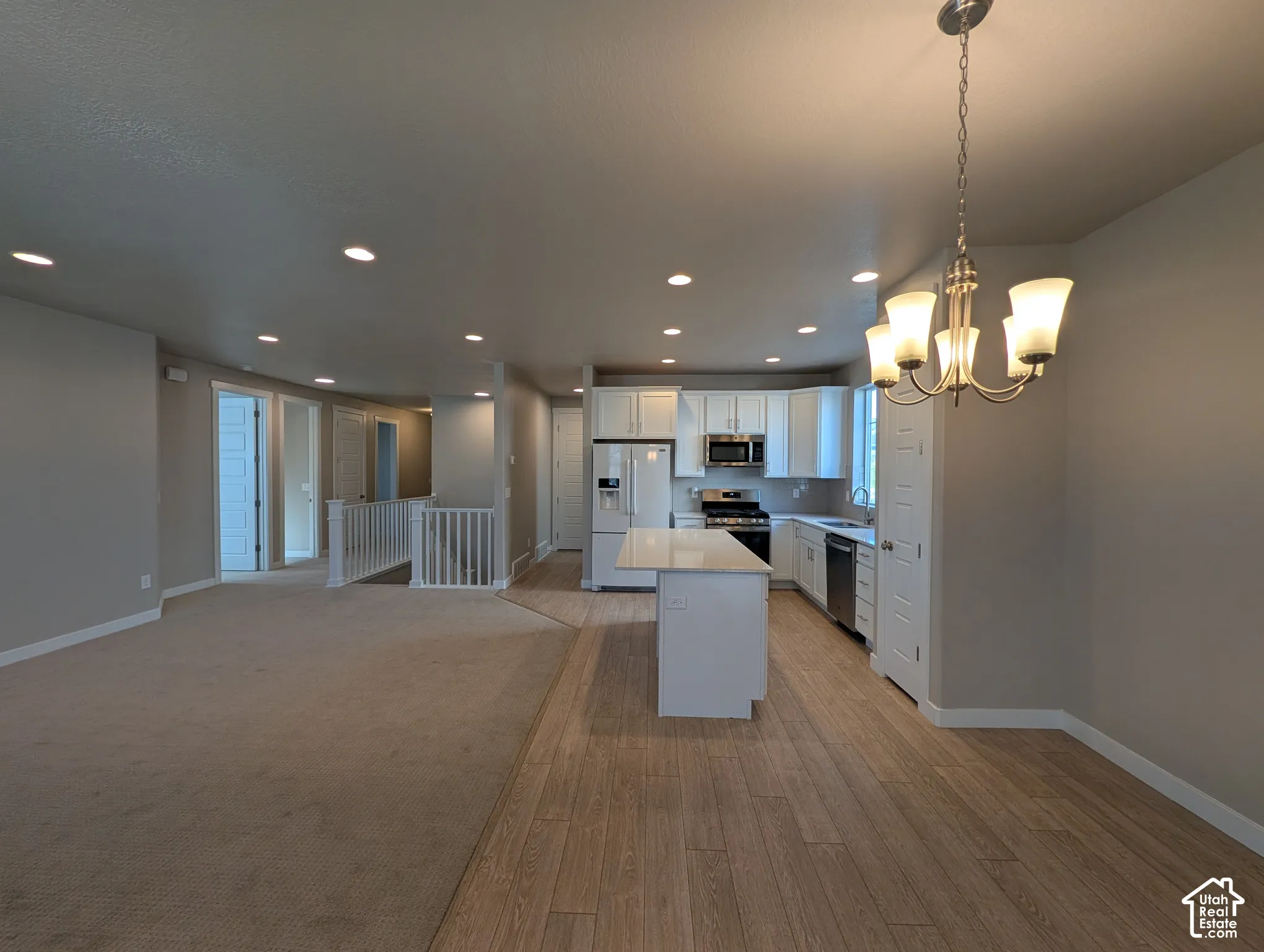 Kitchen featuring a central island with a quartz countertop, white shaker-style cabinetry, recessed lighting, and wood-finish flooring