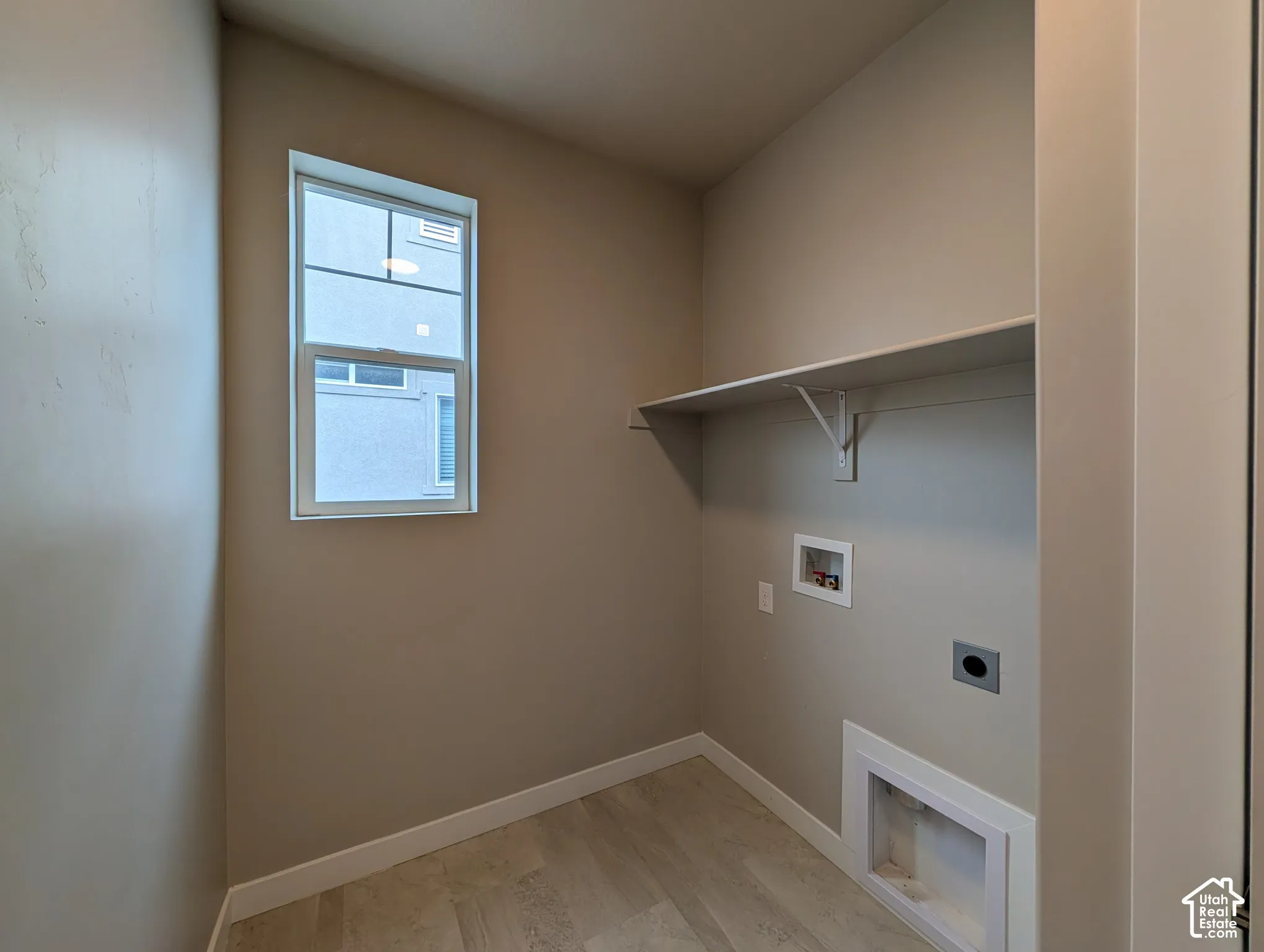 Utility space featuring wood-finish flooring, a single-hung window, and an integrated wall-mounted shelf
