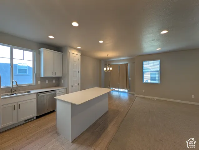 Kitchen featuring white cabinetry, solid-surface countertops, center island, recessed lighting, and wood-finish flooring