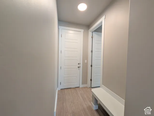 Neutral wall paint, wood-finish flooring, recessed ceiling lighting, and white five-panel interior doors with a built-in white bench
