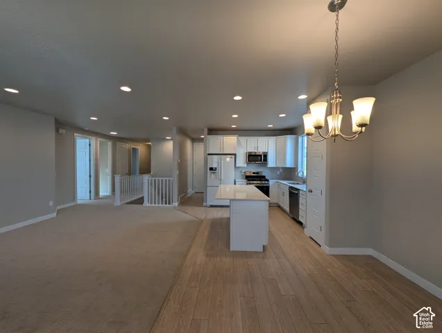 Kitchen featuring a central island with a quartz countertop, white shaker-style cabinetry, recessed lighting, and wood-finish flooring