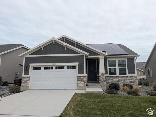 Exterior featuring vertical and horizontal siding, stone veneer accents, an attached two-car garage, roof-mounted solar panels, and a concrete driveway