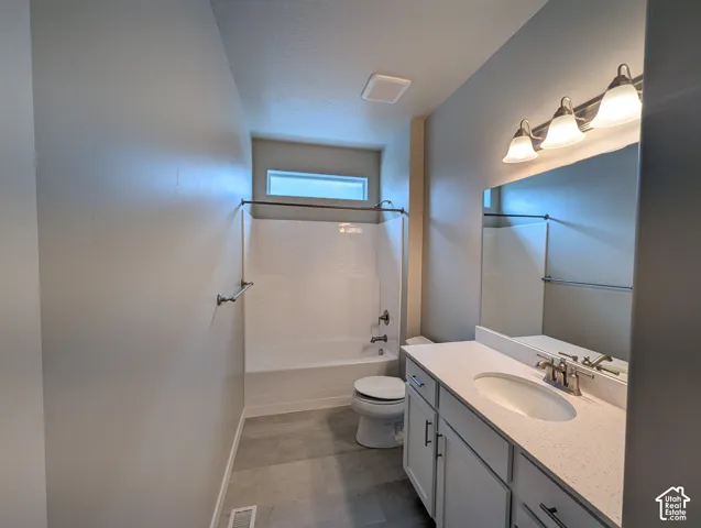 Bathroom featuring white cabinetry, solid-surface countertop with an integrated oval sink, horizontal transom window, and tile-finish flooring