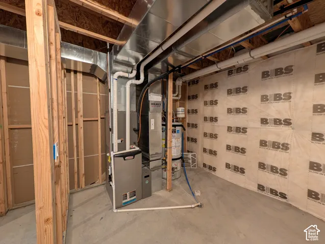 Unfinished utility space featuring exposed wood framing, blown-in insulation, a forced-air furnace, and a water heater