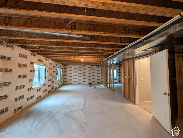 Unfinished lower level featuring exposed wood joist ceilings, concrete flooring, insulated wall panels, and two double-pane windows