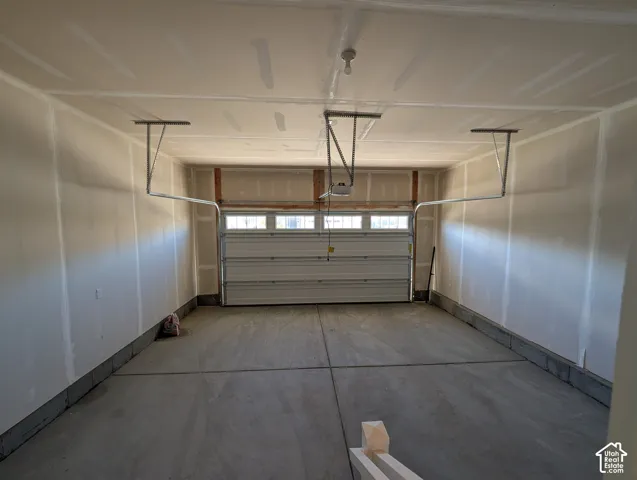 Two-car garage featuring drywall-finished walls, concrete flooring, and an overhead door with integrated windows