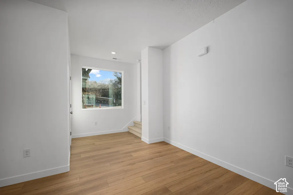 Interior space featuring wood-finish flooring, white walls, and a large window with natural light