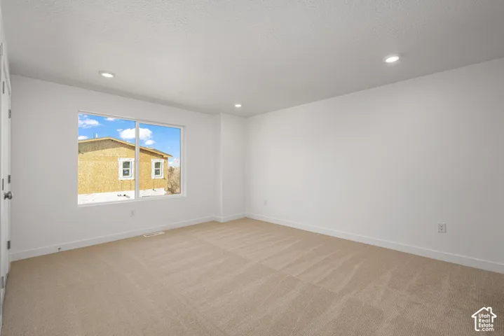 Neutral-toned wall-to-wall carpeting, recessed ceiling lighting, and a large picture window