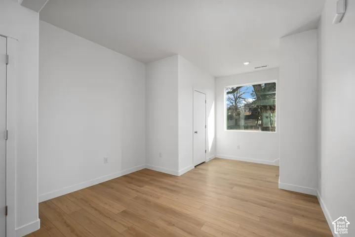 Neutral-toned room featuring wood-finish flooring, a large picture window, and recessed ceiling lighting