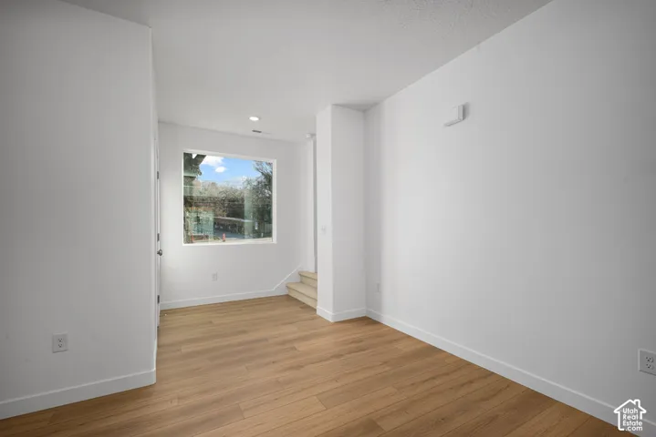 Interior space featuring wood-finish flooring, white walls, and a large window with natural light
