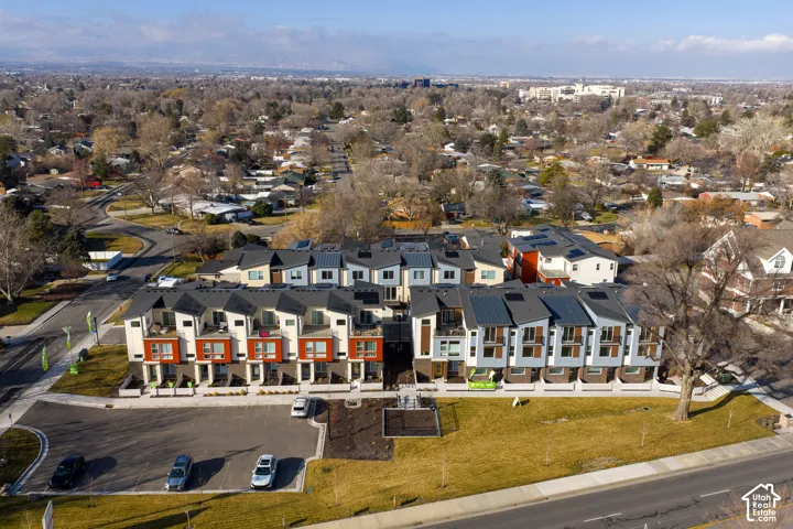 Aerial perspective of a multi-unit residential complex featuring contemporary multi-story architecture, metal roofing, integrated solar panels, private balconies, and dedicated surface parking