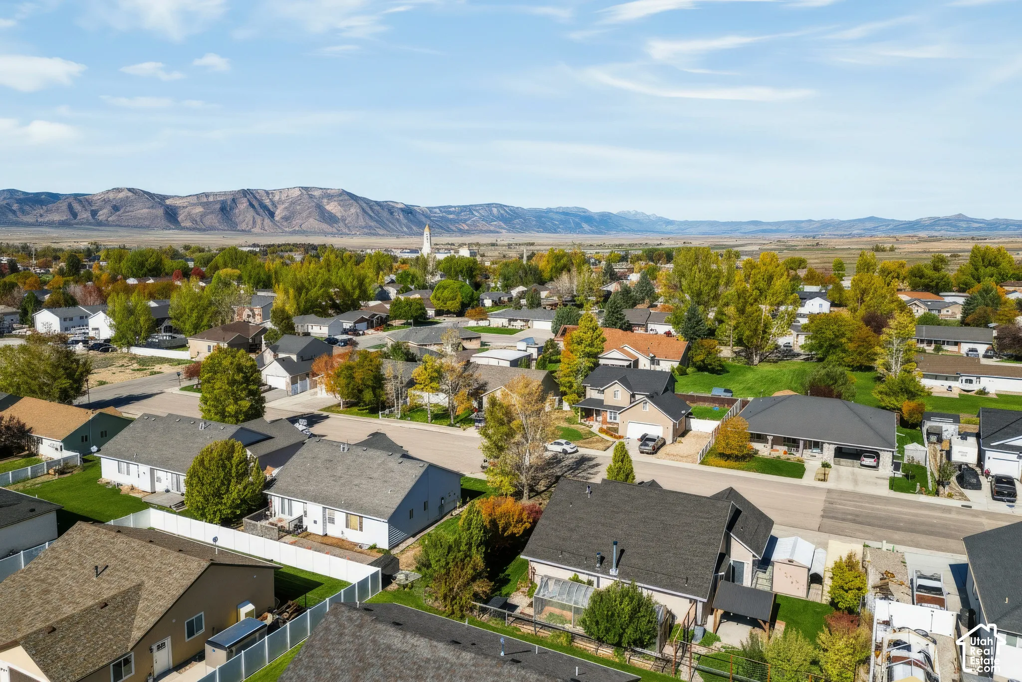 Aerial perspective of the residential neighborhood featuring expansive mountain range horizons and established deciduous trees