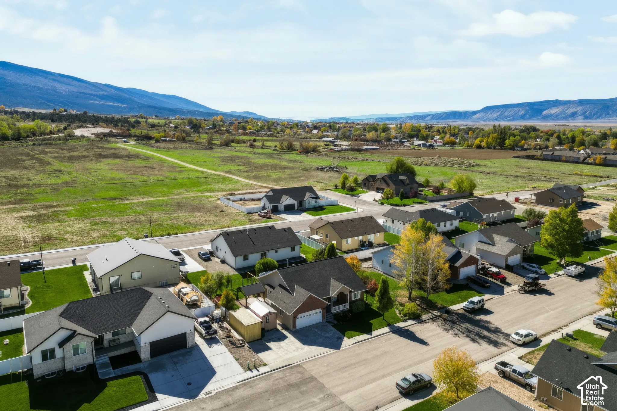 Aerial perspective of residential neighborhood featuring paved streets, attached garages, manicured lawn areas, and prominent mountain backdrop