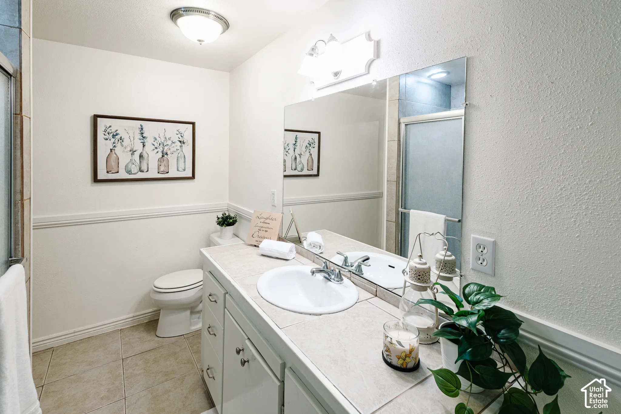 Bathroom featuring a vanity with a tile countertop, integrated basin, large wall-mounted mirror, and tile flooring