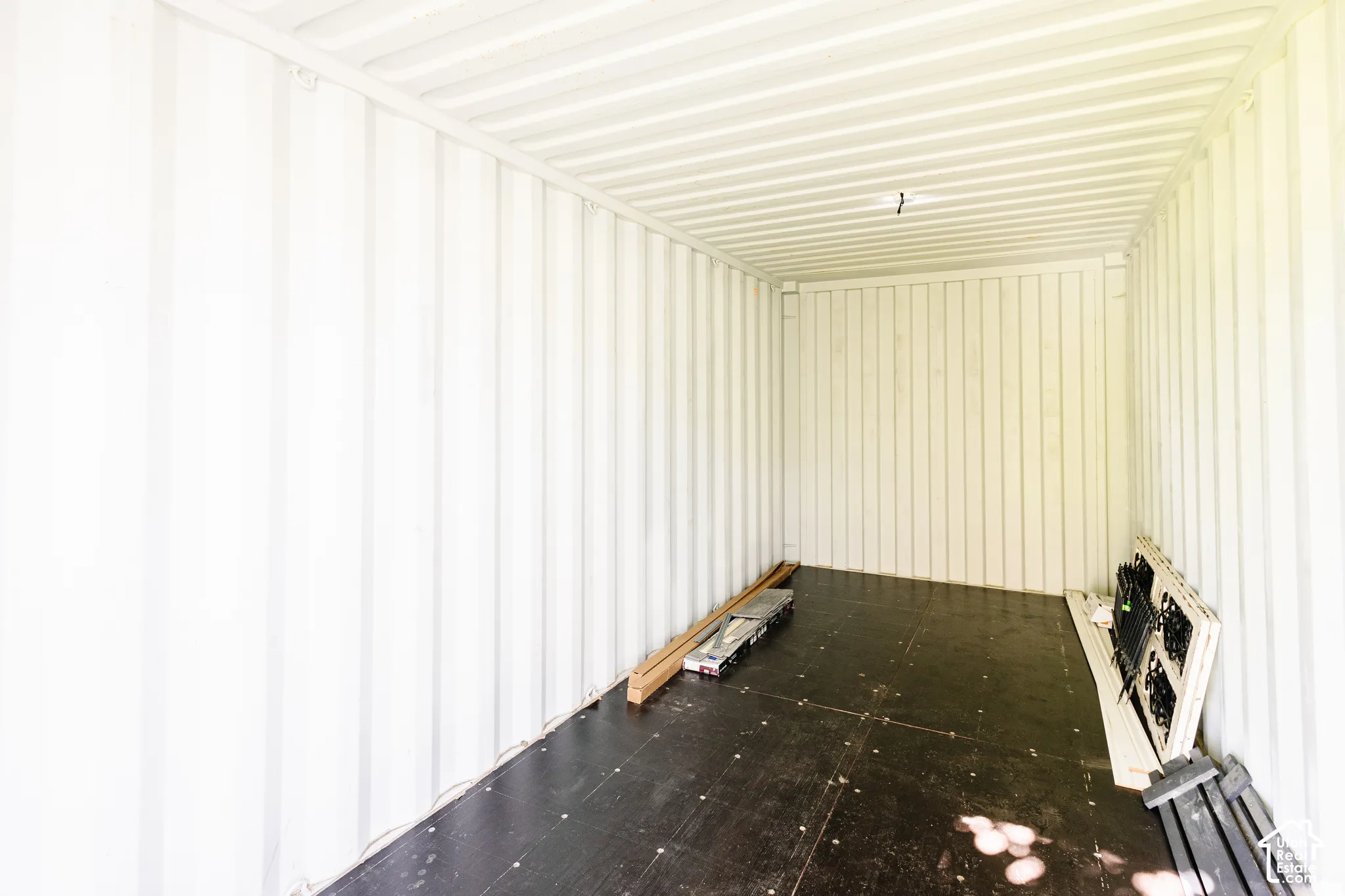 Interior space featuring corrugated metal walls and ceiling finished in white, paired with a dark-toned composite flooring surface