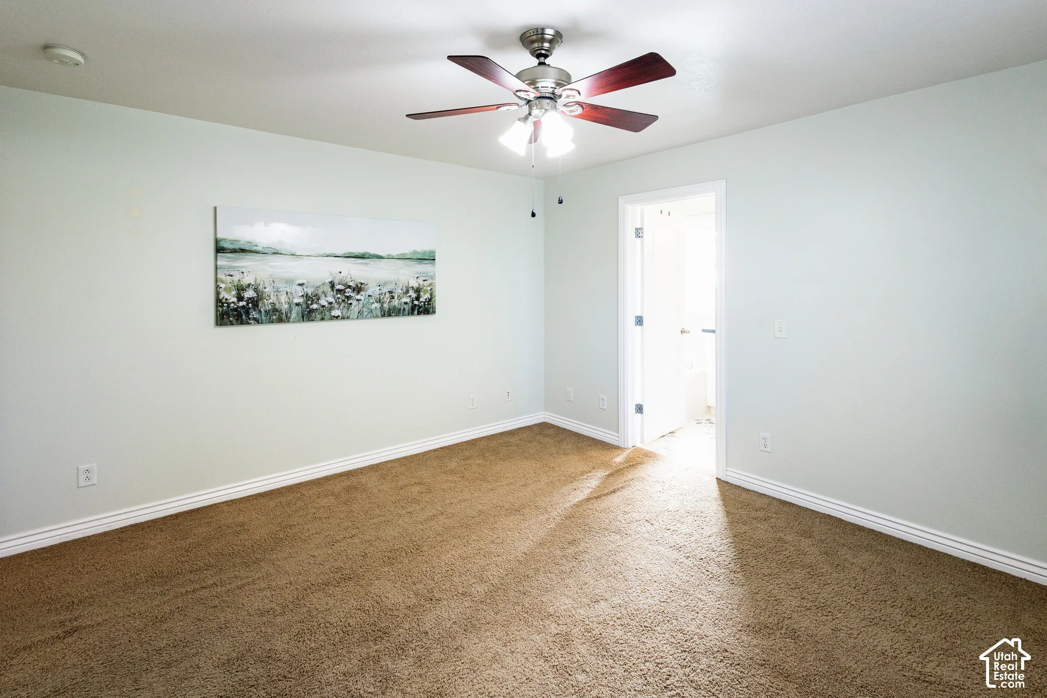 Interior room featuring neutral-toned carpeting, light-colored walls, and a multi-blade ceiling fan with an integrated light fixture