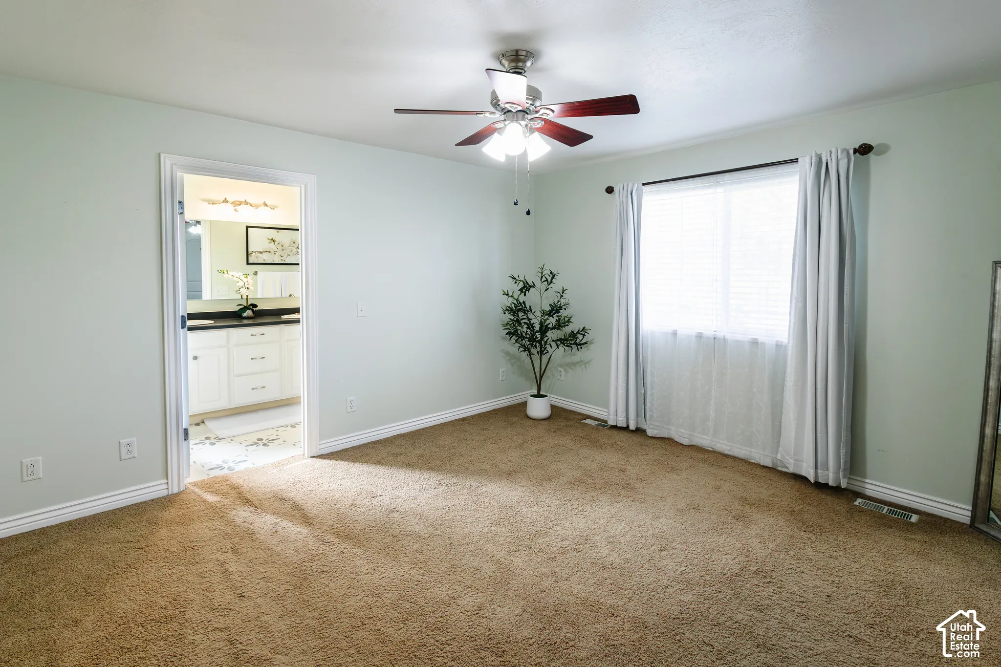 Room featuring carpeting, a centrally mounted ceiling fan with integrated lighting, and a window with hardware for drapery