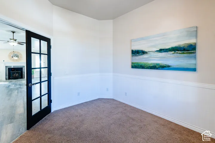 Interior room featuring wall-to-wall carpeting, white beadboard wainscoting, and a black-framed glass panel door
