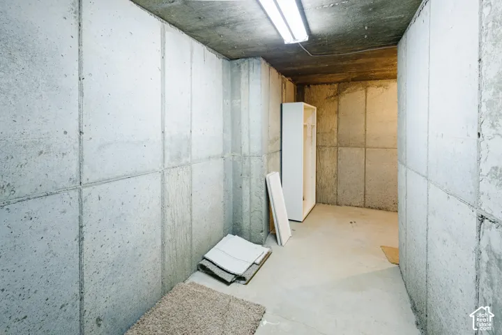 Storage area featuring concrete panel walls, a concrete floor, and an integrated ceiling-mounted light fixture