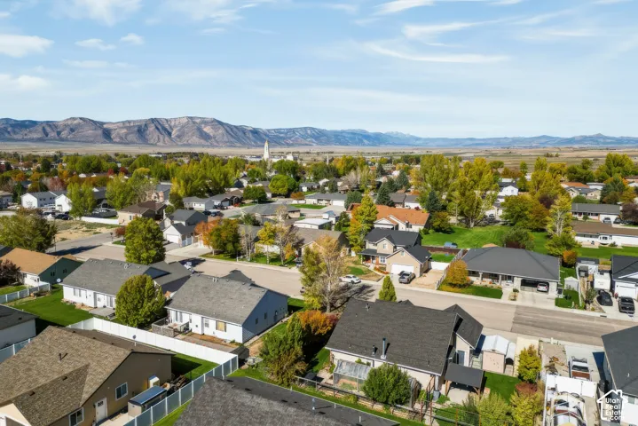 Aerial perspective of the residential neighborhood featuring expansive mountain range horizons and established deciduous trees