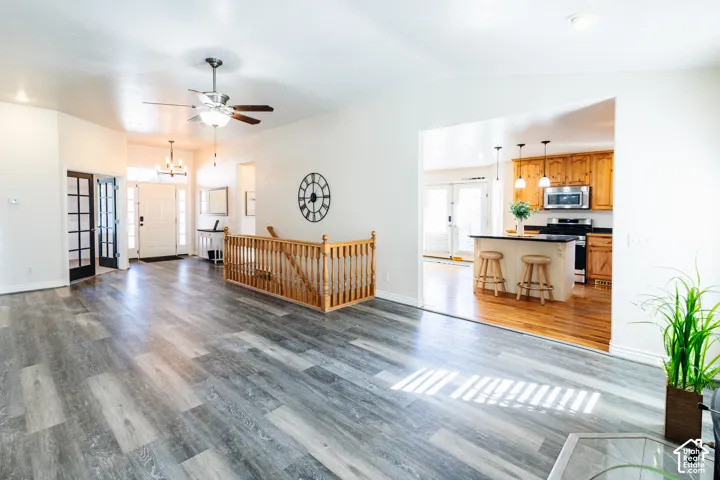 Wood-finish flooring, vaulted ceilings with a central fan, decorative French doors, and a wood banister railing