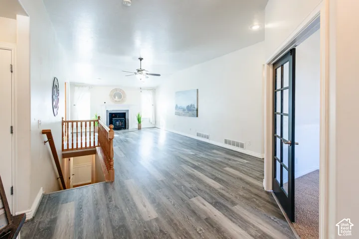 Living area featuring wood-finish flooring, a fireplace, vaulted ceiling with a recessed lighting fixture and ceiling fan, and a French door with glass panels