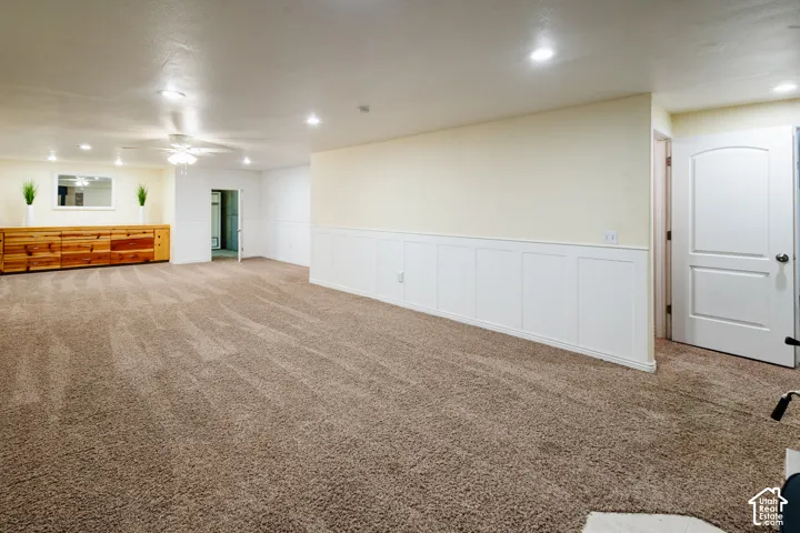 Spacious room featuring carpeting, recessed lighting, white wainscoting, and a built-in wooden cabinet