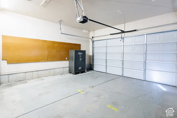 Attached two-car garage featuring a sectional overhead door, concrete flooring, and wall-mounted pegboard organization system