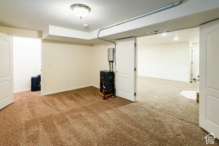 Neutral-toned carpeting, white interior doors, and wainscot paneling