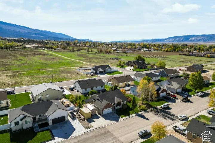 Aerial perspective of residential neighborhood featuring paved streets, attached garages, manicured lawn areas, and prominent mountain backdrop