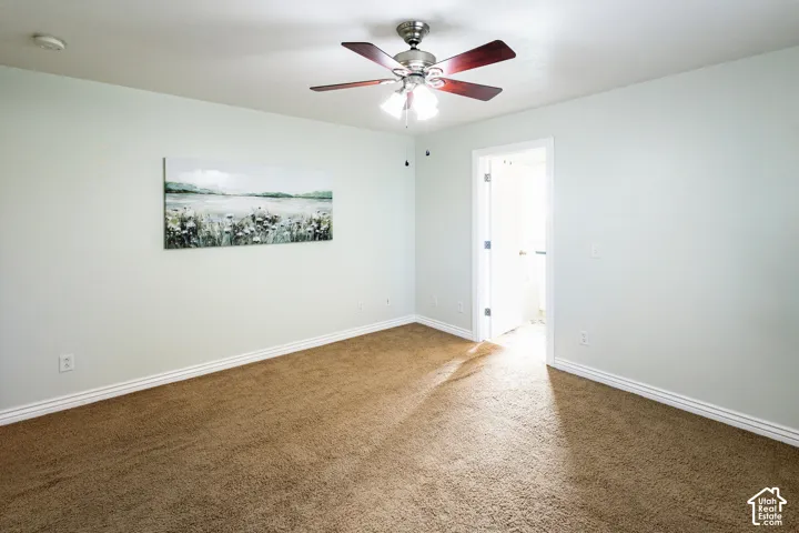 Interior room featuring neutral-toned carpeting, light-colored walls, and a multi-blade ceiling fan with an integrated light fixture