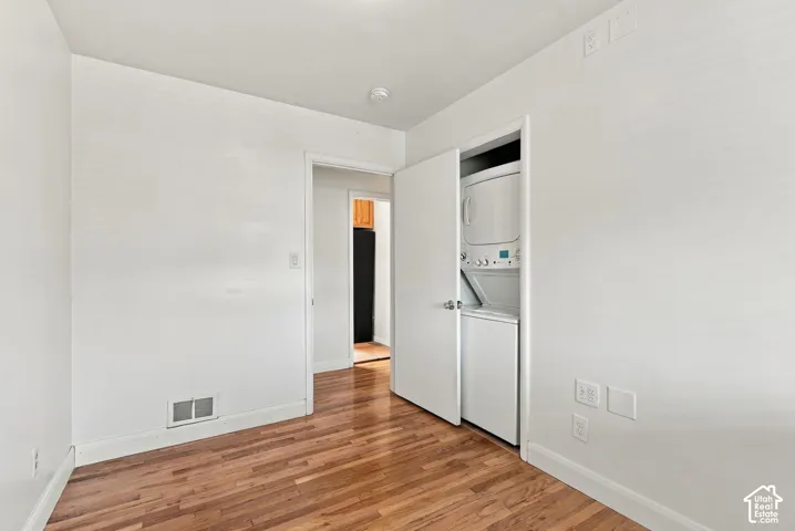 Stacked laundry unit enclosed in a closet with white swing doors and wood-finish flooring