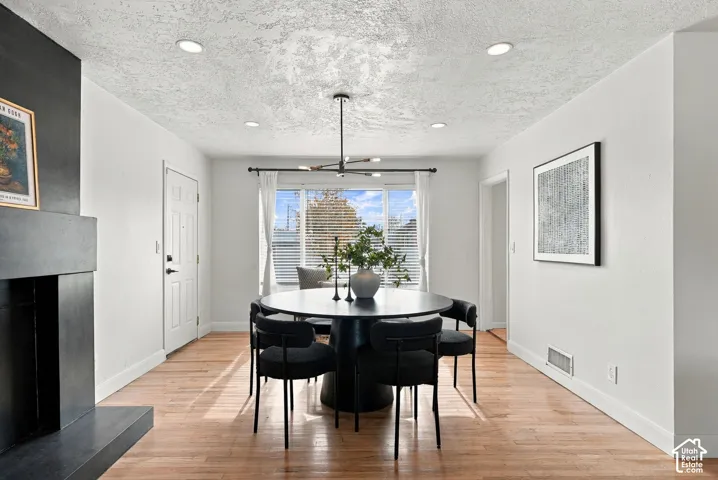 Room featuring wood-finish flooring, a matte black fireplace surround, modern multi-arm chandelier, and recessed lighting