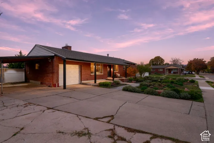 Single-story brick exterior featuring a covered carport, an attached one-car garage, and a xeriscaped front yard