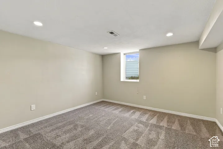 Neutral-toned interior space featuring recessed ceiling lighting, wall-to-wall carpeting, and a single vertical window